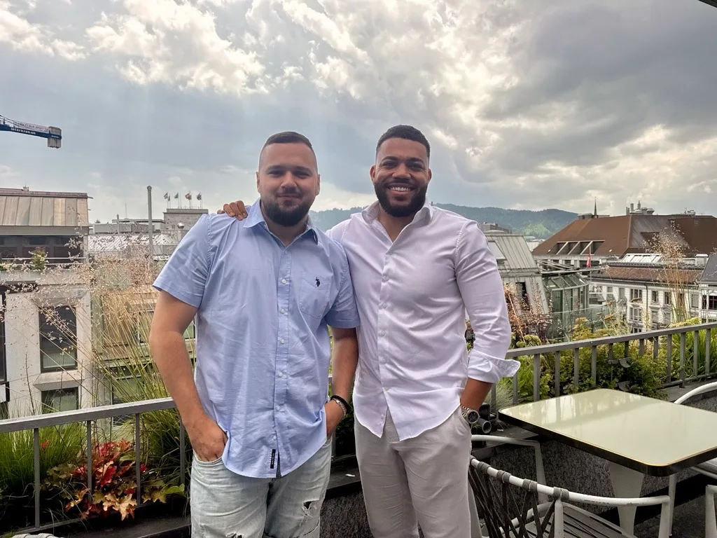 Zwei Männer auf einer Terrasse vor dem Wolkenhimmel